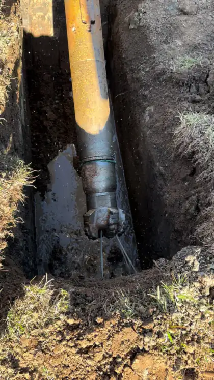 Drill string entering the ground from a pit during a rock shot in Canberra.