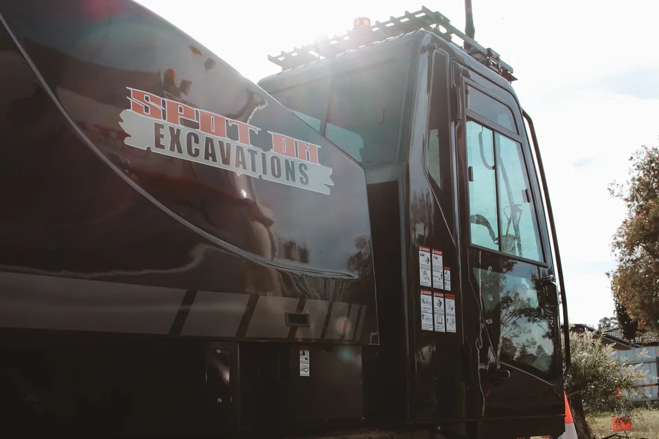 Spot On Excavations branding on the black drilling rig in the sunlight.